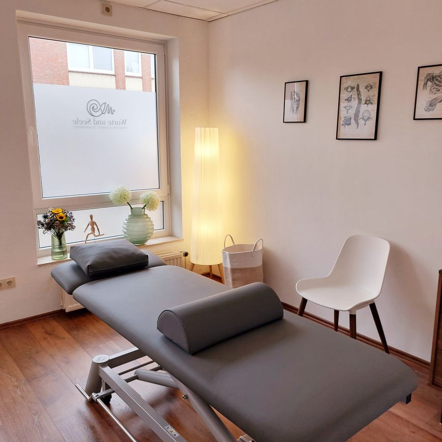 Behandlungsraum mit Behandlungsliege und anatomischen Abbildungen